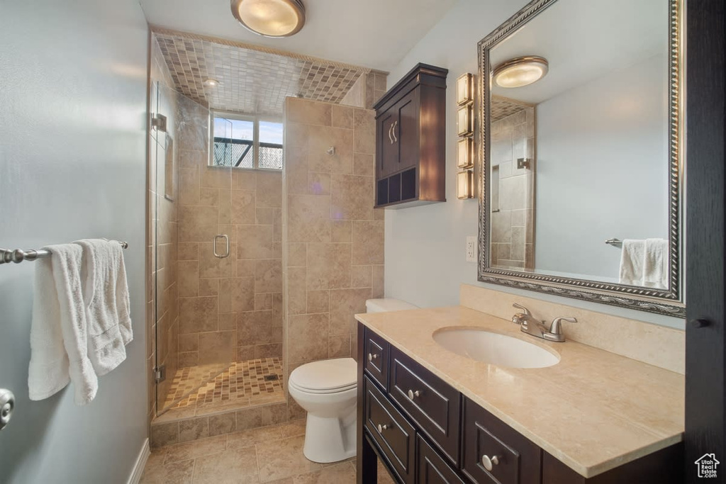 Bathroom featuring toilet, an enclosed shower, tile floors, and vanity with extensive cabinet space