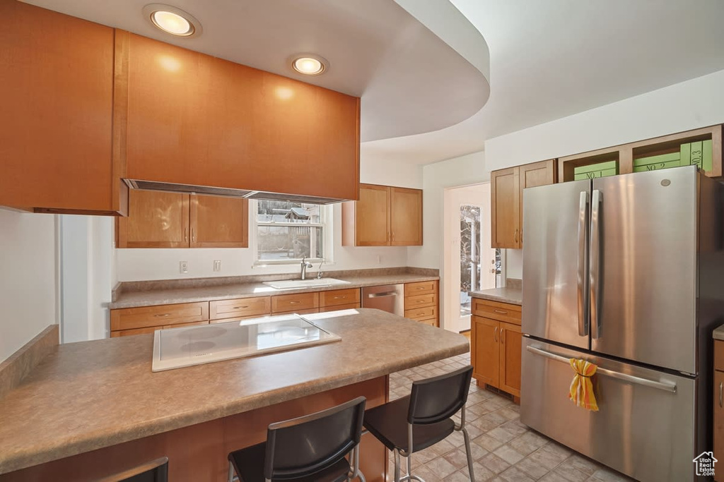 Kitchen with a breakfast bar area, sink, appliances with stainless steel finishes, and light tile floors