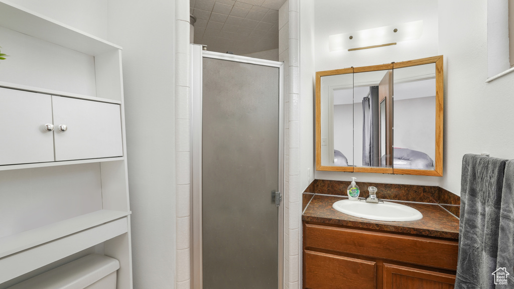 Bathroom featuring toilet, a shower with shower door, and vanity with extensive cabinet space