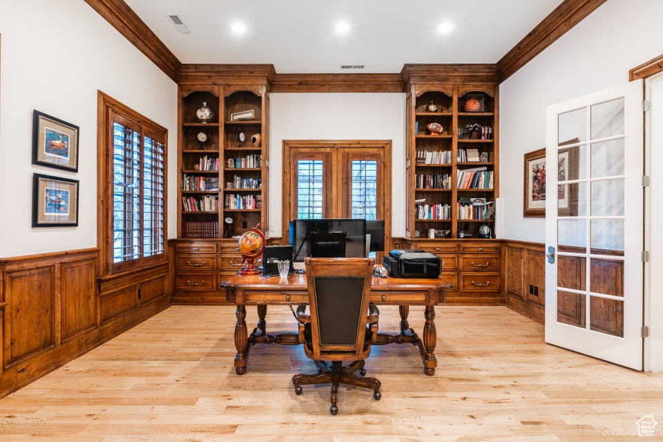 Home office featuring plenty of natural light, light hardwood / wood-style floors, and french doors