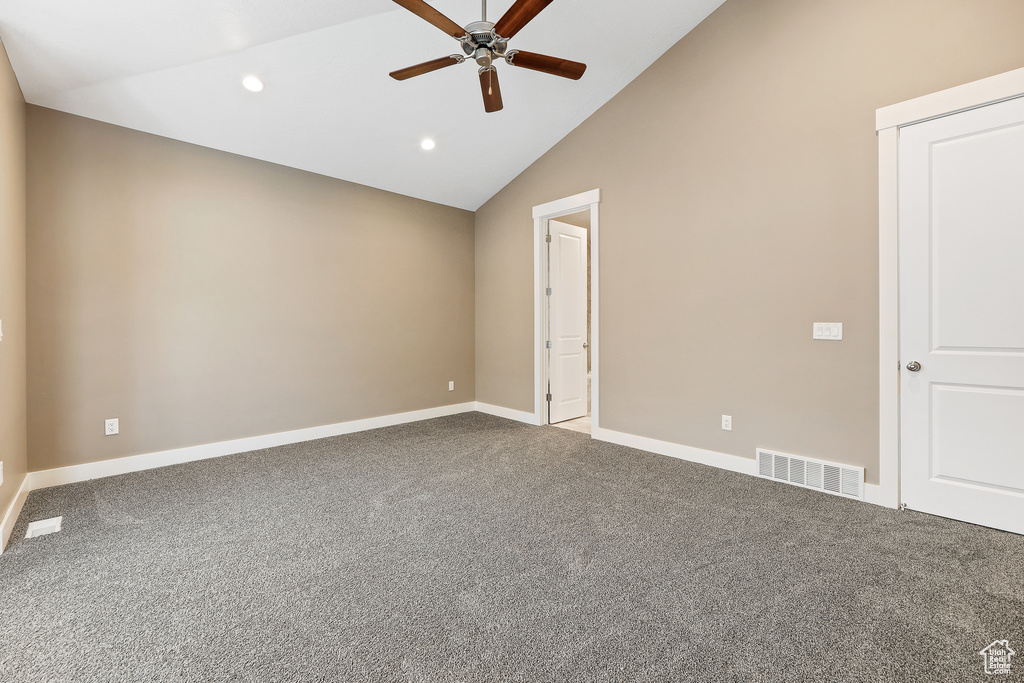 Carpeted spare room featuring high vaulted ceiling and ceiling fan