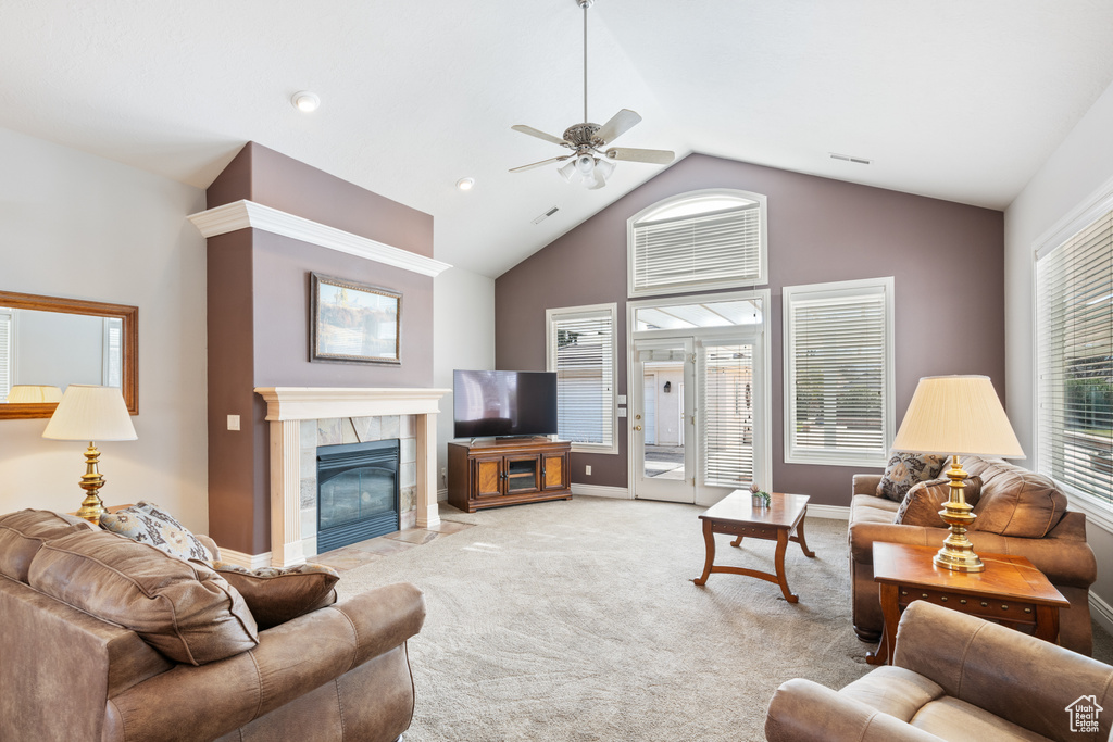 Carpeted living room featuring a fireplace, high vaulted ceiling, and ceiling fan