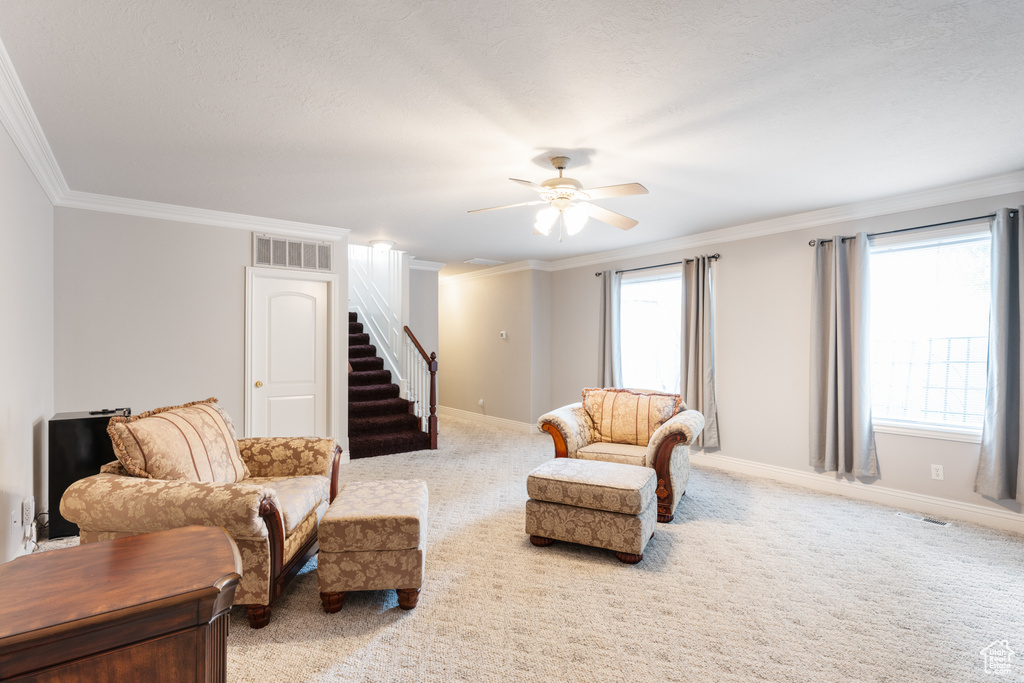 Sitting room with crown molding, ceiling fan, and light colored carpet