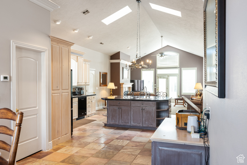 Kitchen with hanging light fixtures, a skylight, light tile floors, and high vaulted ceiling