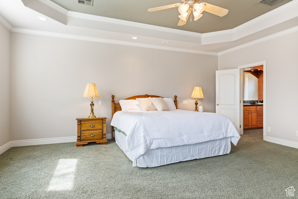 Carpeted bedroom featuring ensuite bathroom, crown molding, ceiling fan, and a tray ceiling