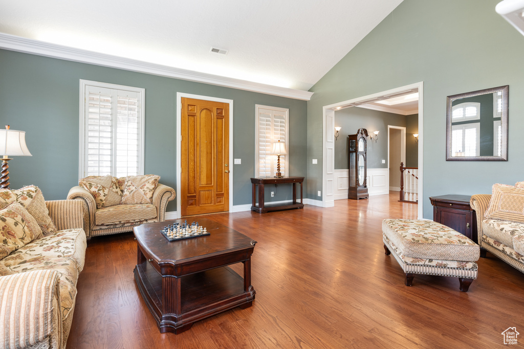 Living room featuring dark hardwood / wood-style flooring, high vaulted ceiling, and ornamental molding