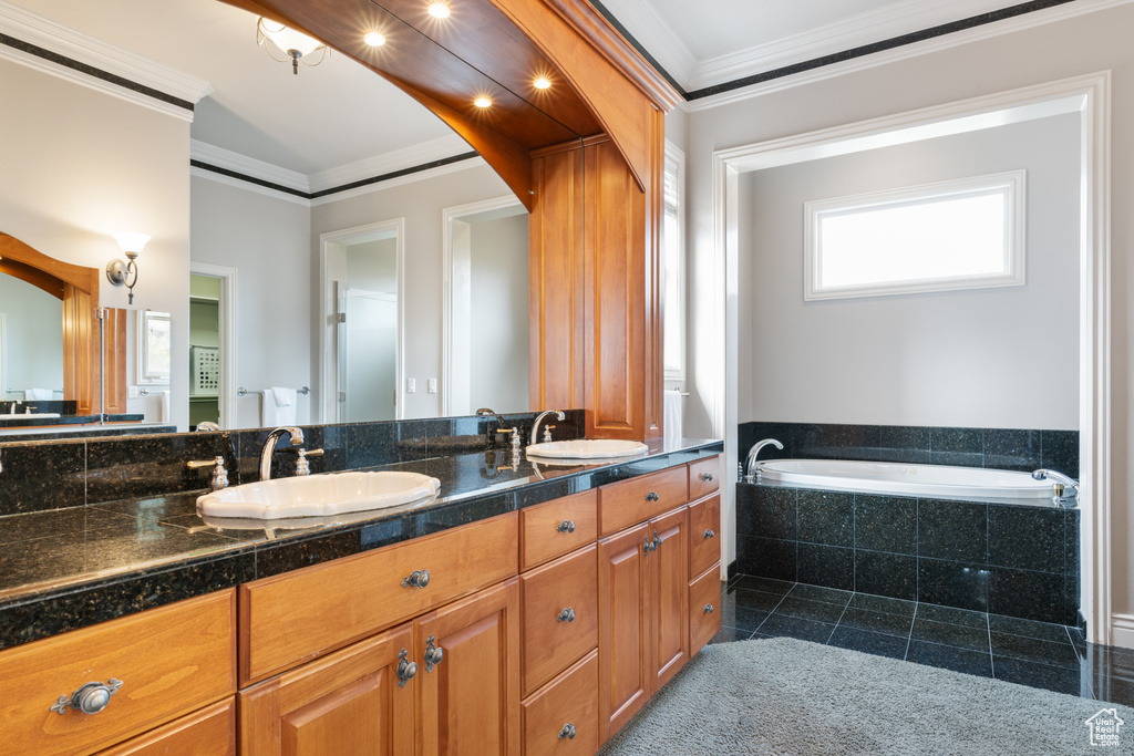 Bathroom featuring dual bowl vanity, ornamental molding, tile flooring, and tiled bath