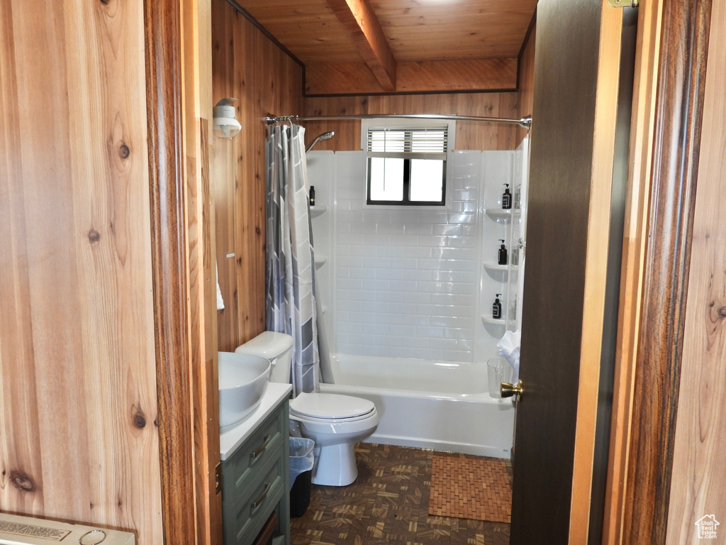 Full bathroom with vanity, wooden walls, toilet, wooden ceiling, and shower / tub combo