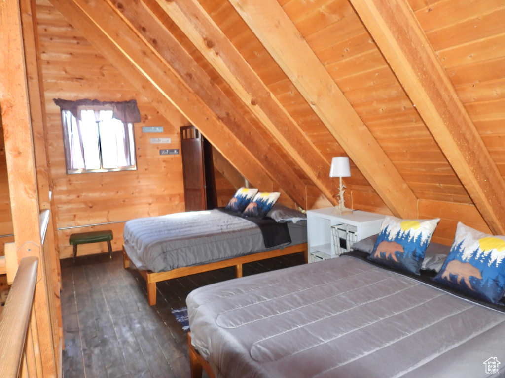 Unfurnished bedroom with dark hardwood / wood-style flooring, vaulted ceiling with beams, and wood walls