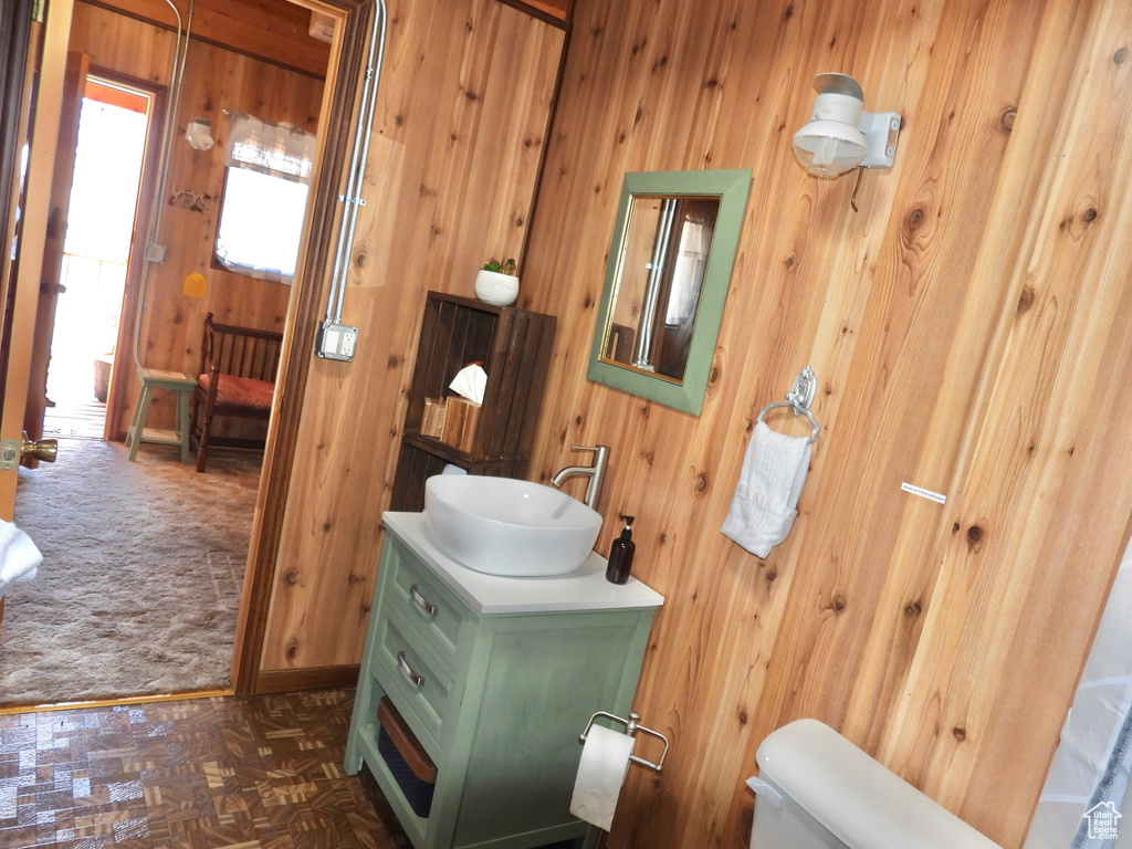 Bathroom featuring vanity, wooden walls, parquet flooring, and toilet