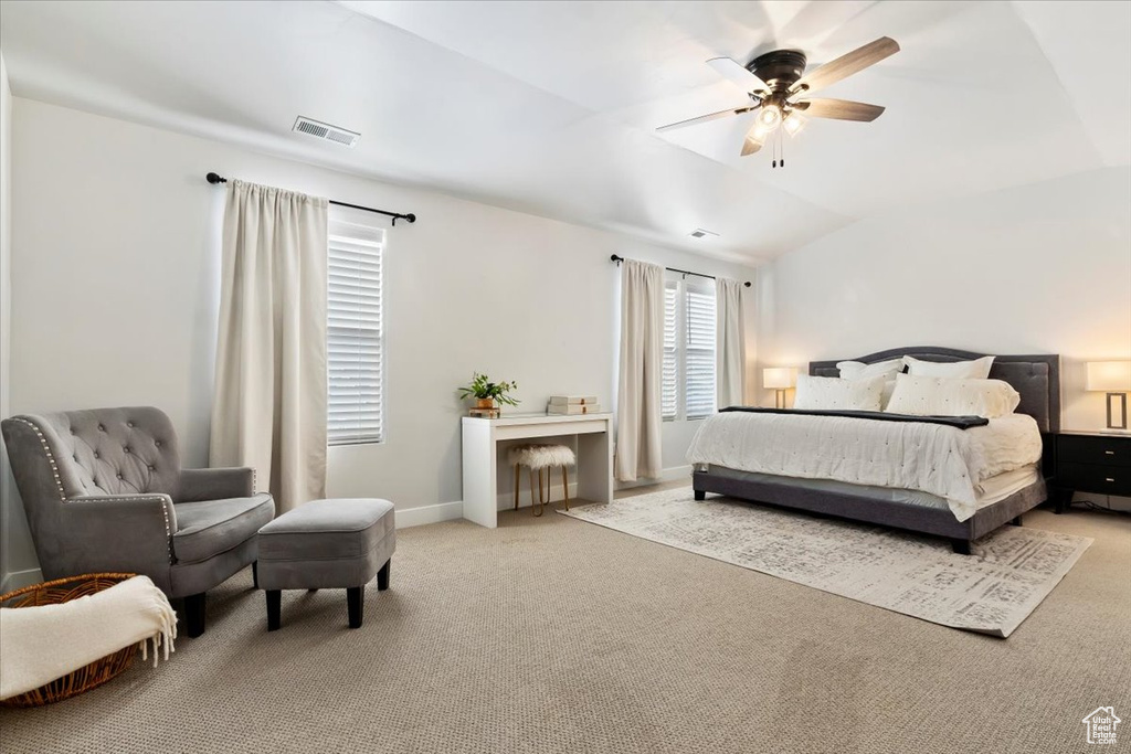 Bedroom with light carpet, ceiling fan, and vaulted ceiling