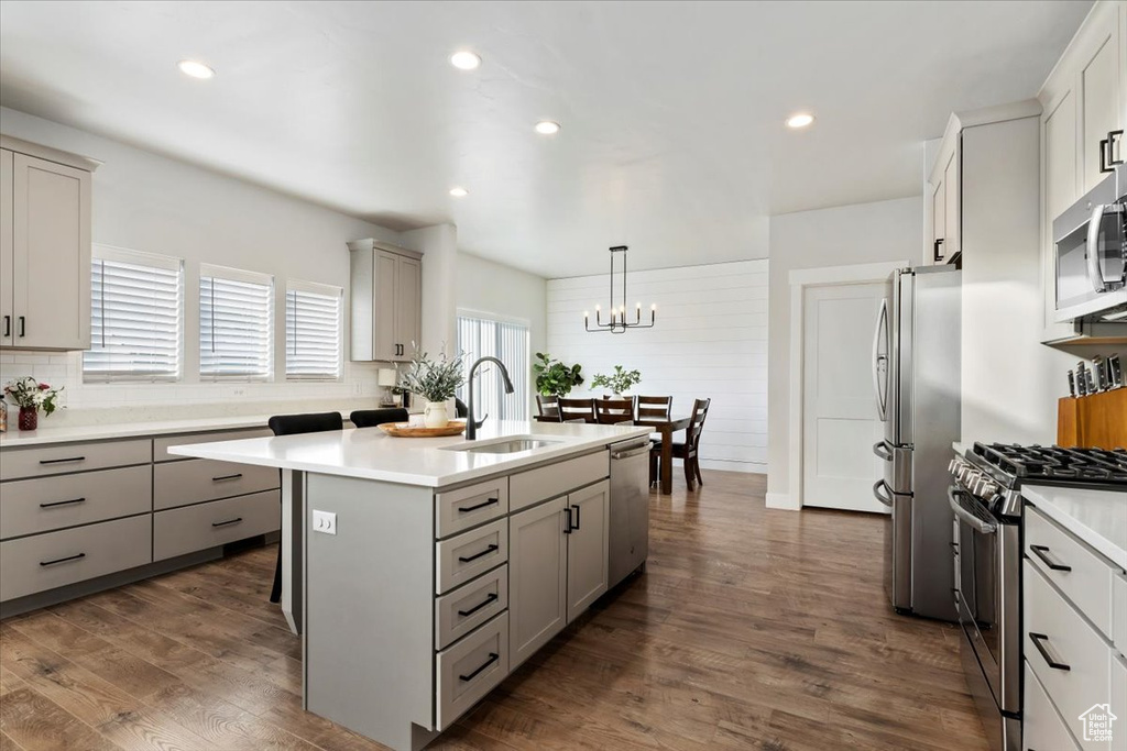 Kitchen with hanging light fixtures, an inviting chandelier, dark hardwood / wood-style floors, sink, and appliances with stainless steel finishes
