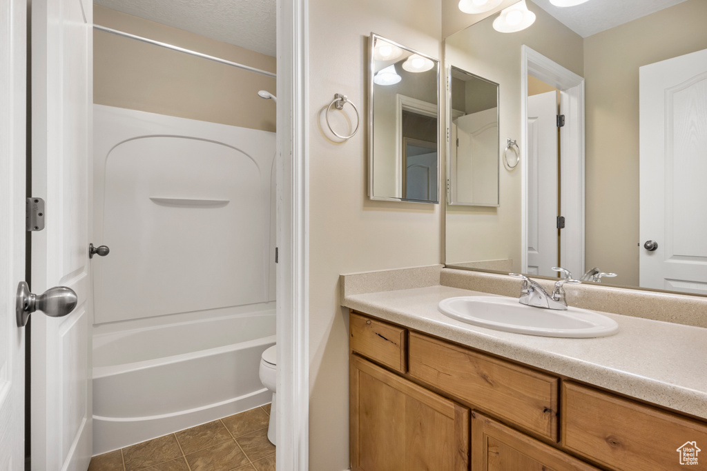 Full bathroom with shower / washtub combination, tile floors, vanity with extensive cabinet space, and toilet