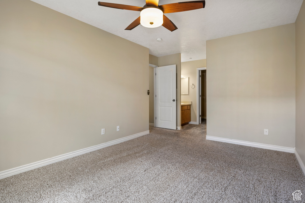 Unfurnished bedroom featuring connected bathroom, ceiling fan, and dark carpet