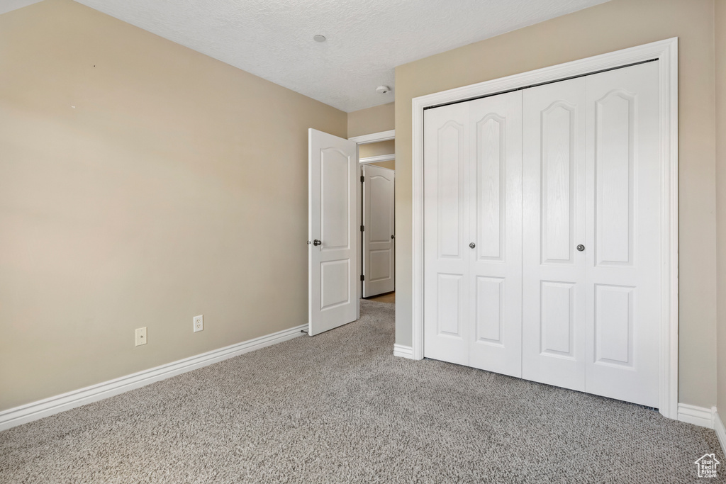 Unfurnished bedroom featuring a closet and light colored carpet
