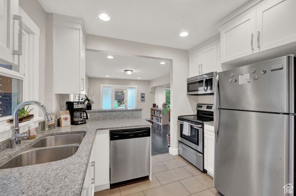 Kitchen featuring white cabinetry, sink, light stone countertops, and stainless steel appliances