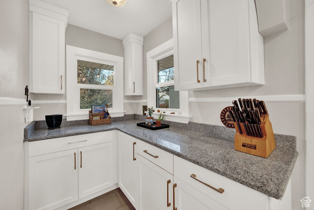 Kitchen featuring white cabinetry, dark stone counters, and tile floors