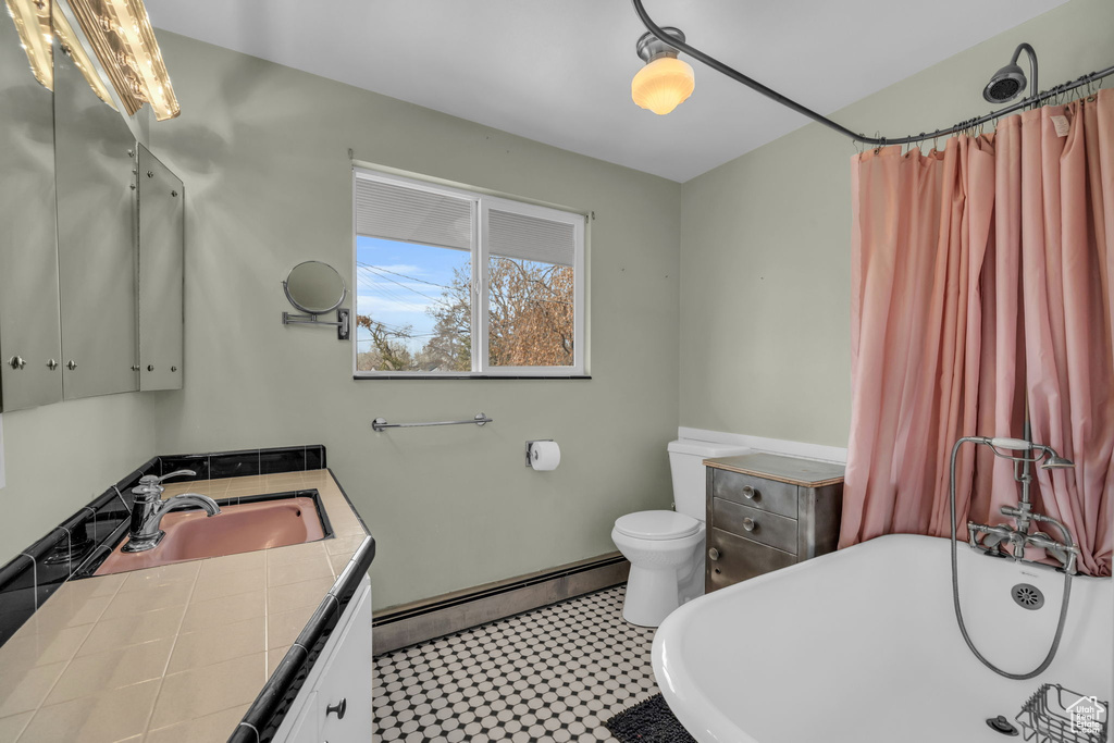 Bathroom with large vanity, a baseboard radiator, tile floors, and toilet