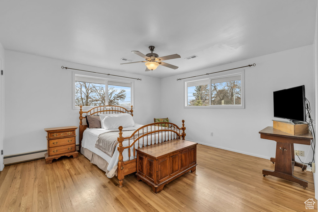 Bedroom with light wood-type flooring, a baseboard radiator, and ceiling fan
