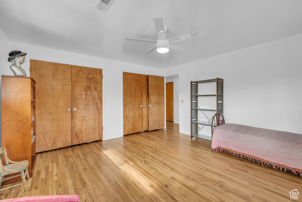 Unfurnished bedroom with multiple closets, light hardwood / wood-style floors, and ceiling fan