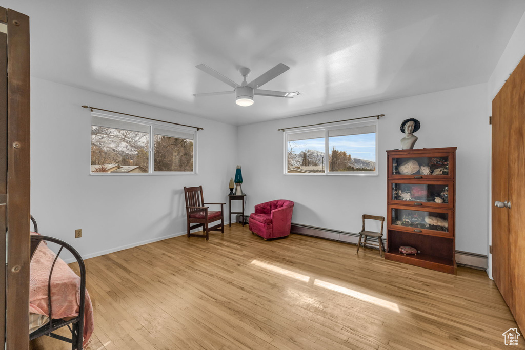 Sitting room with baseboard heating, light hardwood / wood-style flooring, and ceiling fan