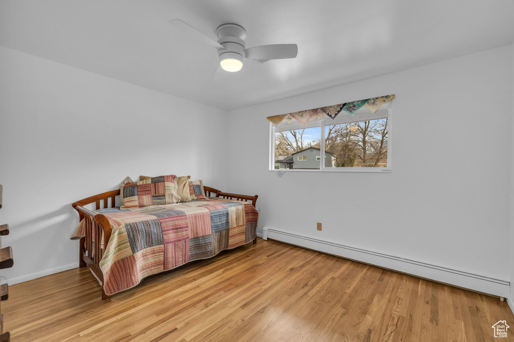 Bedroom with light hardwood / wood-style flooring, ceiling fan, and a baseboard radiator