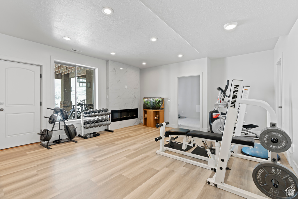 Exercise area with light hardwood / wood-style floors and a fireplace