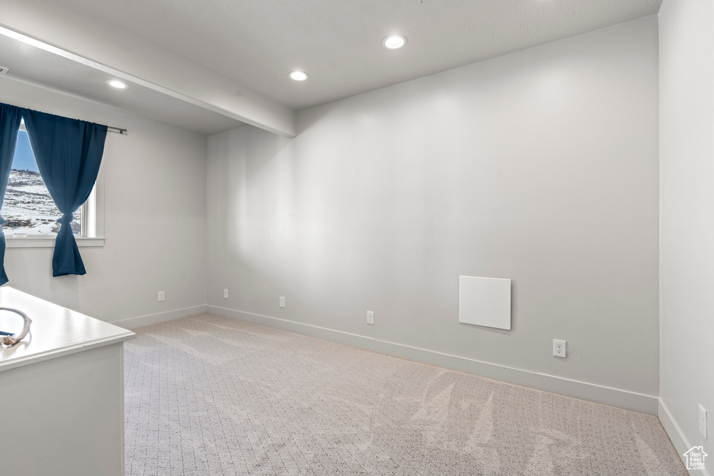 Unfurnished room featuring beamed ceiling and light colored carpet