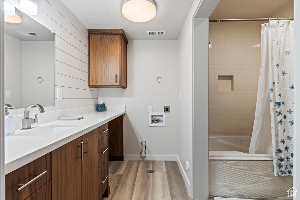 Bathroom with vanity, shower / bath combination with curtain, and hardwood / wood-style flooring
