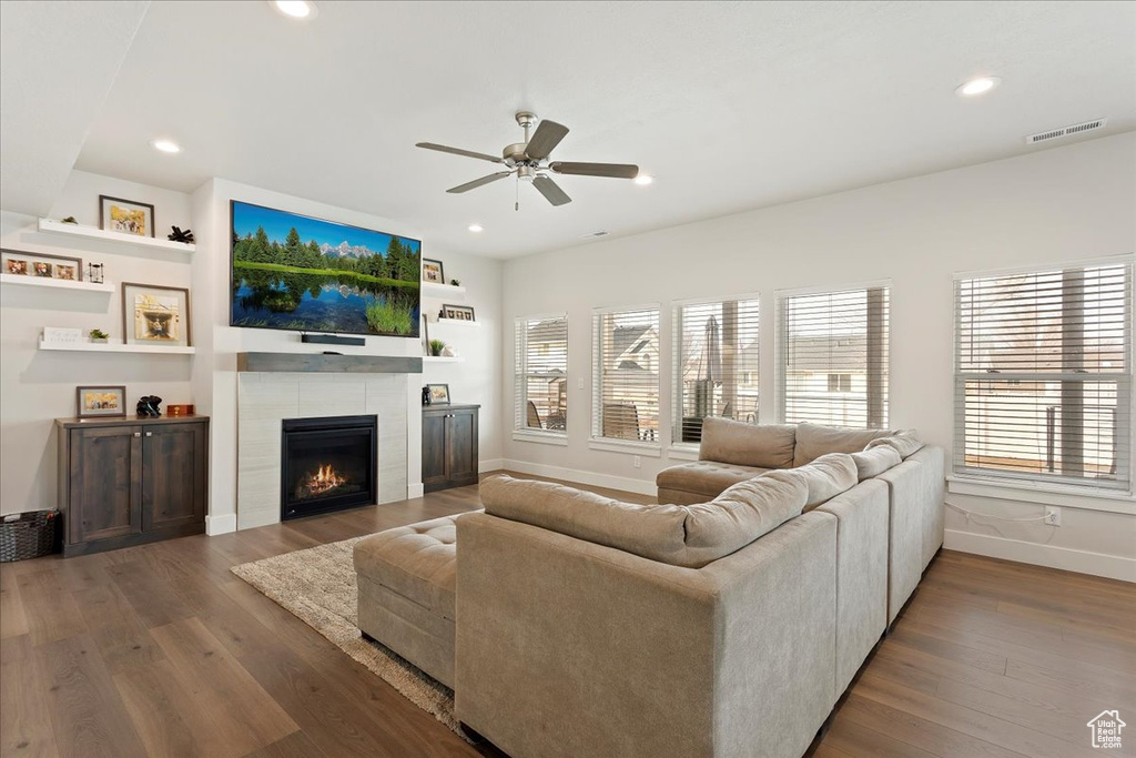 Living room featuring dark hardwood / wood-style floors, ceiling fan, and a tile fireplace