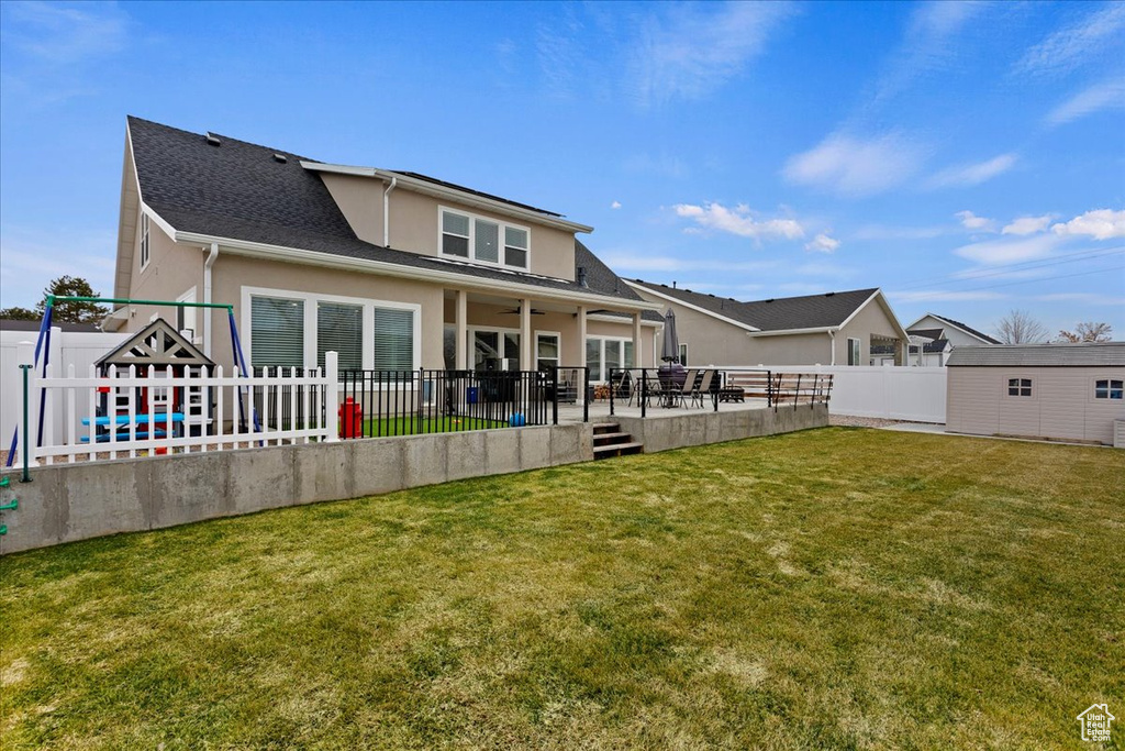 Back of property featuring a patio area, a wooden deck, and a lawn