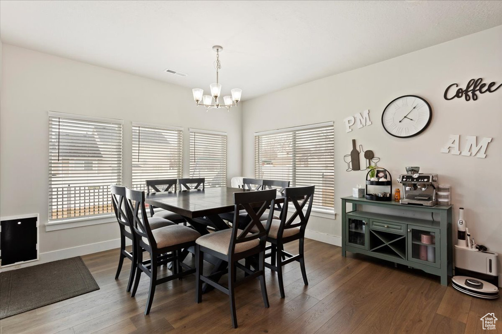 Dining room featuring an inviting chandelier, a wealth of natural light, and dark hardwood / wood-style floors