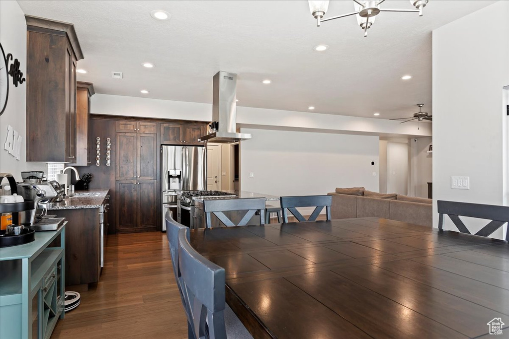 Dining space with dark hardwood / wood-style flooring, sink, and ceiling fan with notable chandelier