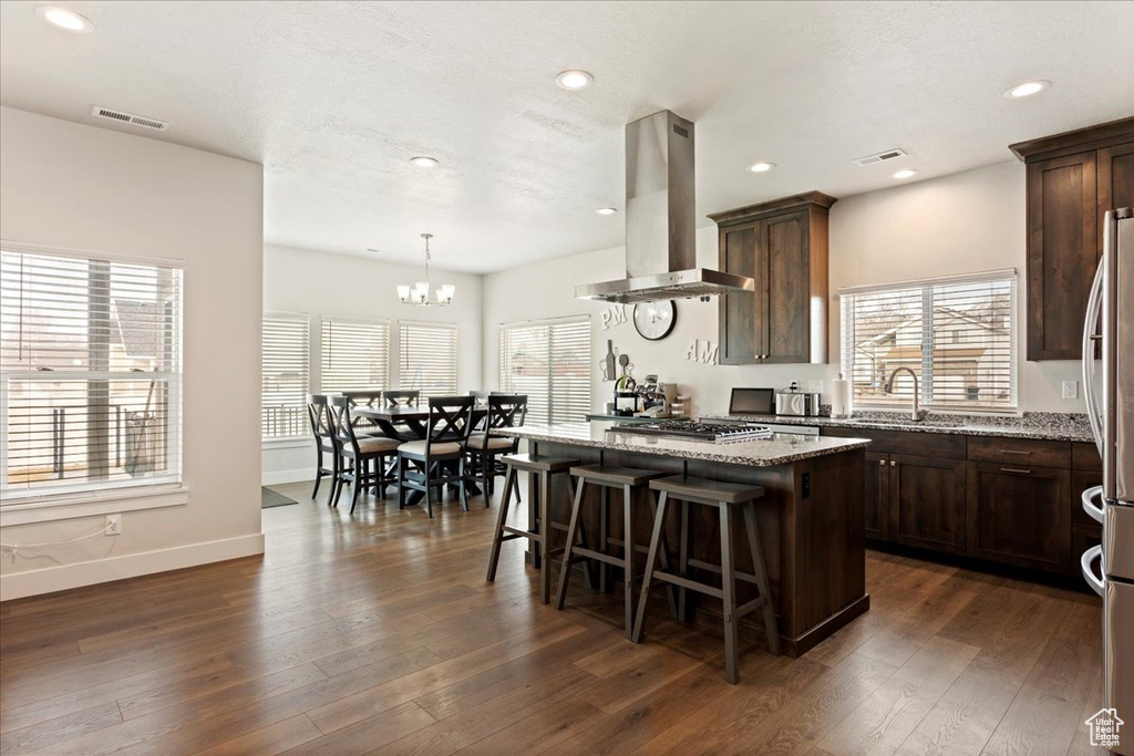 Kitchen featuring a kitchen island, light stone countertops, dark hardwood / wood-style flooring, and island exhaust hood
