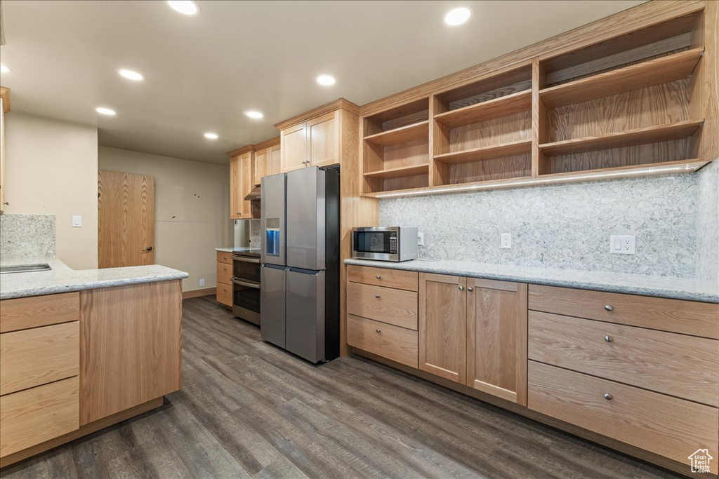 Kitchen featuring light brown cabinets, light stone countertops, tasteful backsplash, dark hardwood / wood-style flooring, and stainless steel appliances