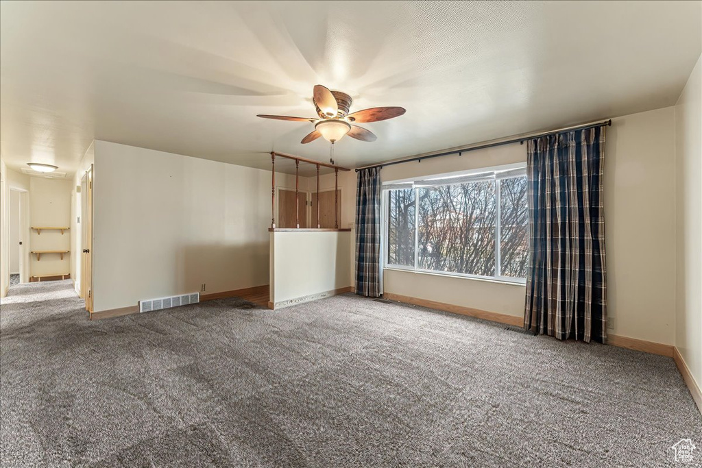 Unfurnished room with ceiling fan and dark carpet