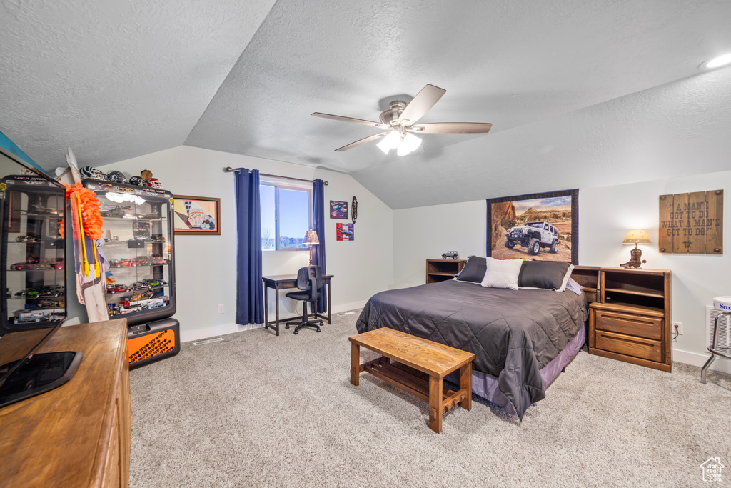 Bedroom featuring ceiling fan, light colored carpet, vaulted ceiling, and a textured ceiling