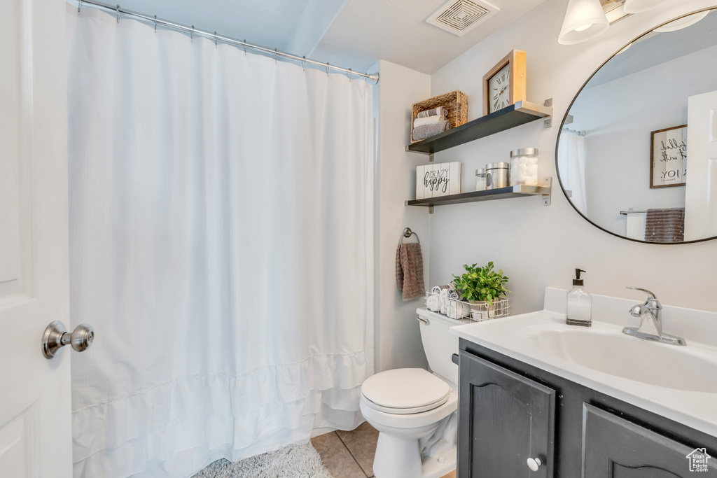 Bathroom featuring toilet, vanity with extensive cabinet space, and tile floors
