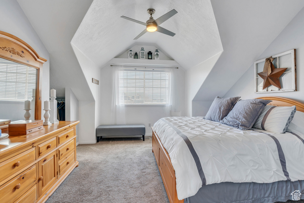 Carpeted bedroom with ceiling fan and vaulted ceiling