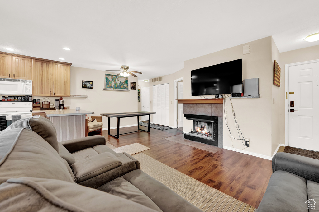 Living room featuring ceiling fan, hardwood / wood-style flooring, and a tiled fireplace