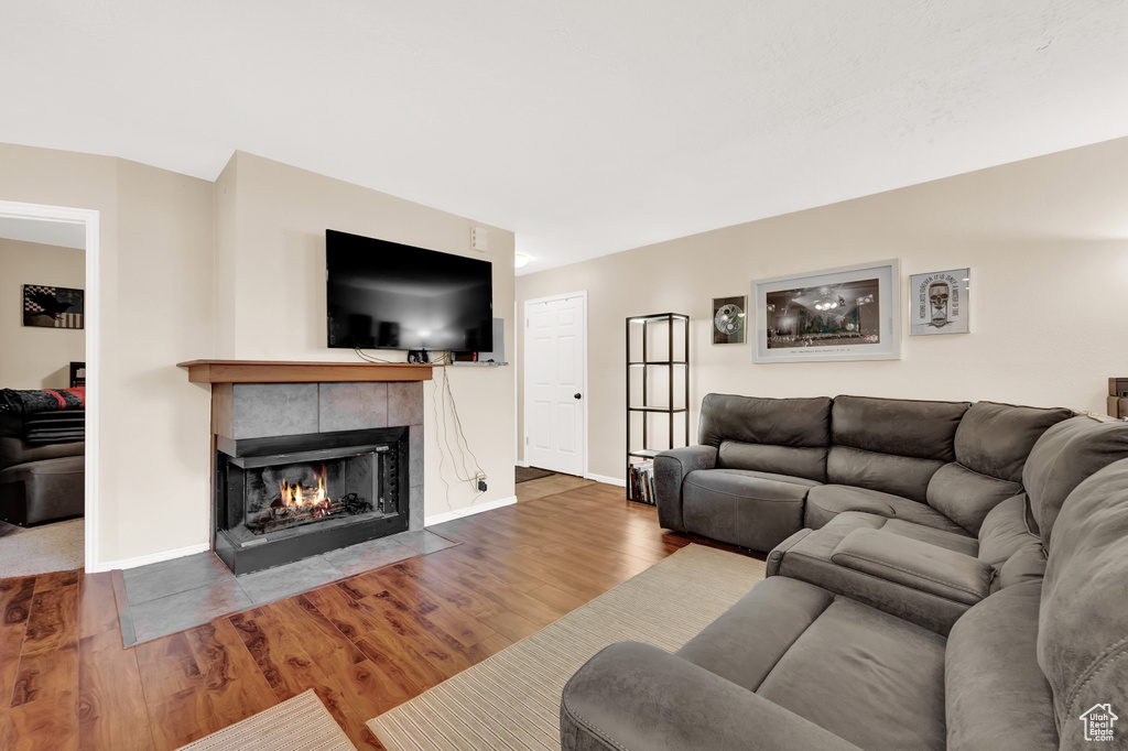 Living room with a tiled fireplace and hardwood / wood-style flooring