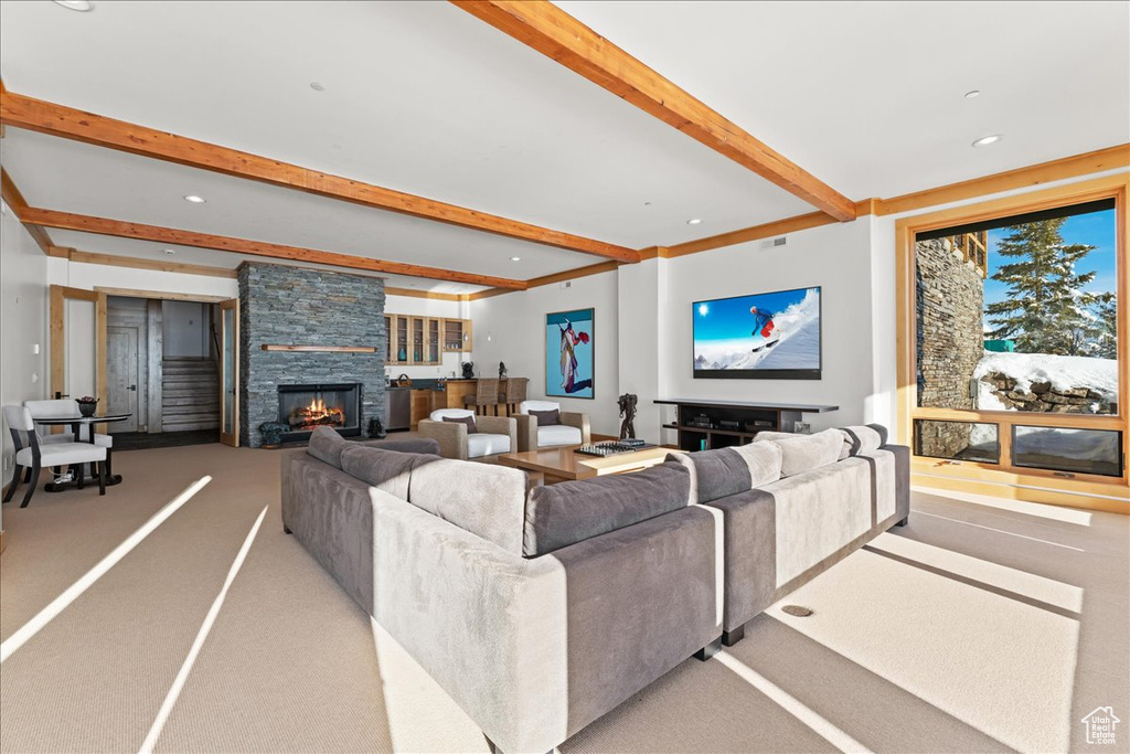 Carpeted living room with a stone fireplace and beamed ceiling