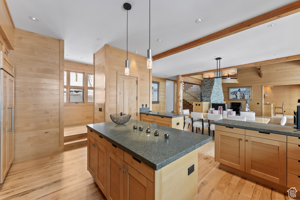 Kitchen with a kitchen island, light hardwood / wood-style floors, decorative light fixtures, and wood walls