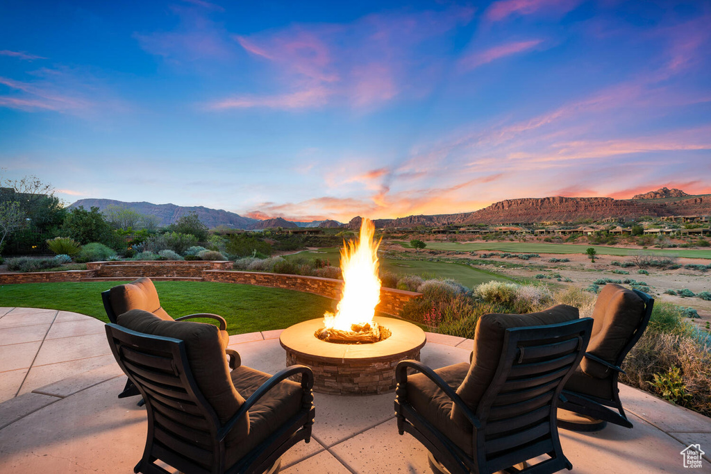 Patio terrace at dusk featuring a lawn, an outdoor fire pit, and a mountain view