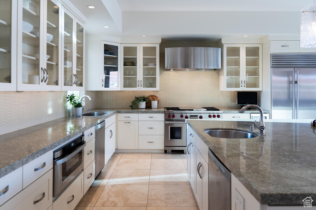 Kitchen featuring tasteful backsplash, premium appliances, and white cabinetry