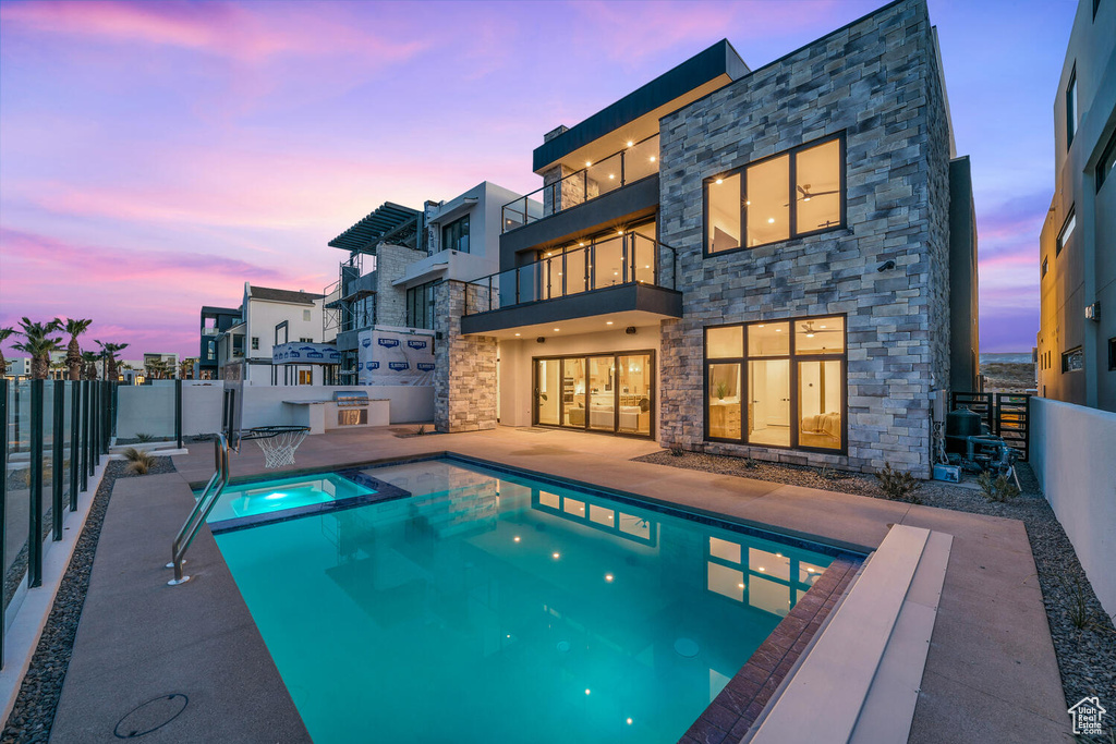 Pool at dusk with a patio and an in ground hot tub