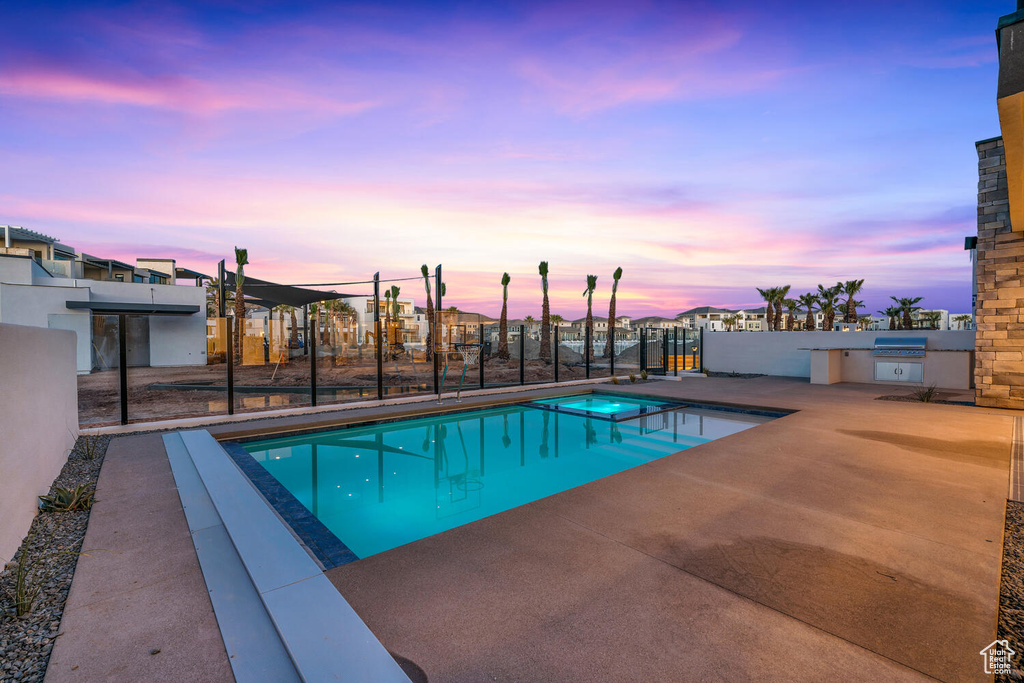 Pool at dusk with a patio area, grilling area, and area for grilling