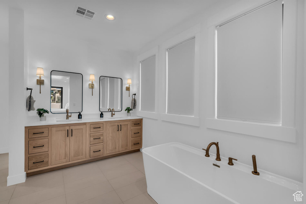 Bathroom with a tub, tile floors, and dual vanity