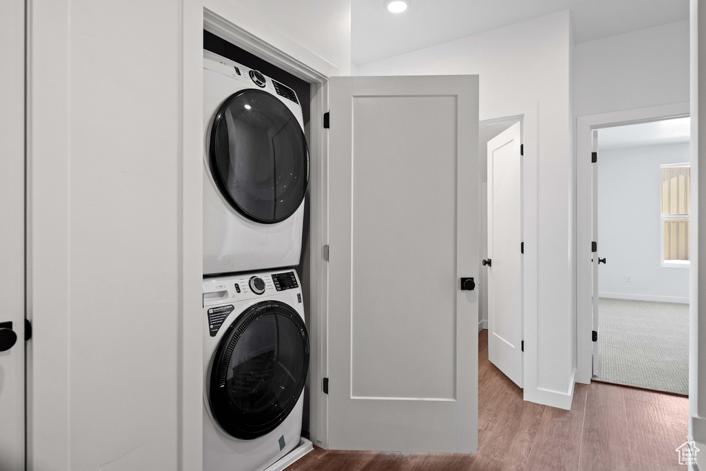 Laundry area with light hardwood / wood-style flooring and stacked washer and dryer
