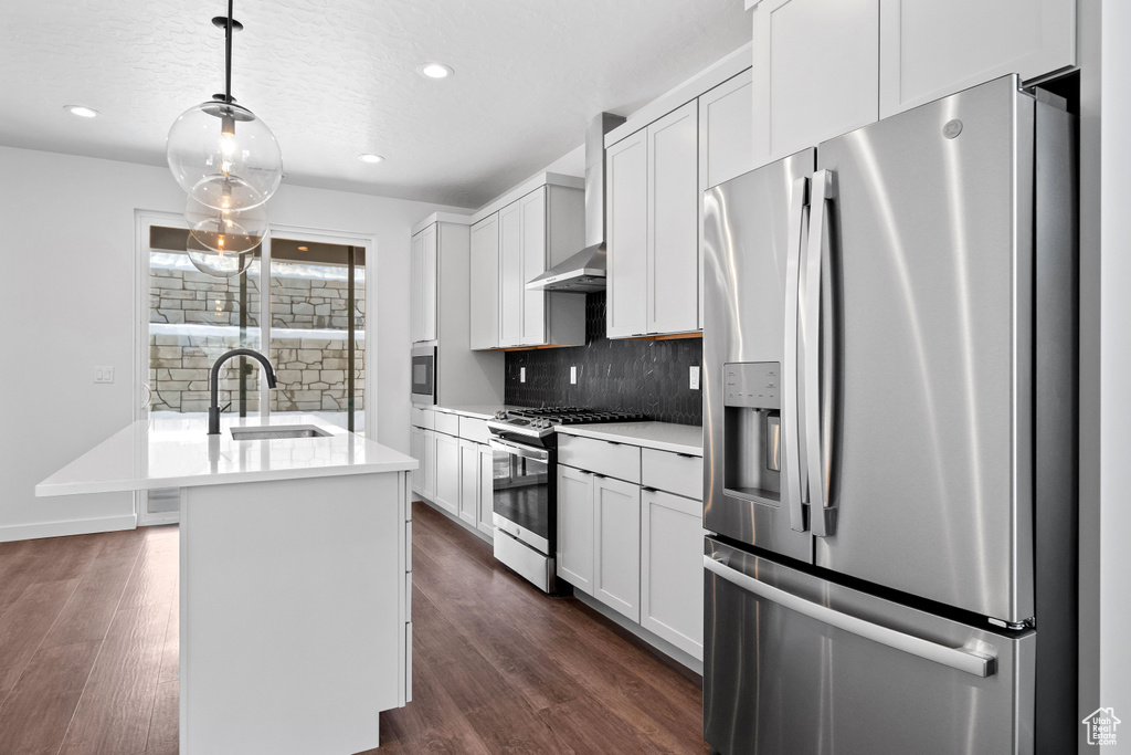 Kitchen featuring dark hardwood / wood-style floors, stainless steel appliances, backsplash, and a center island with sink